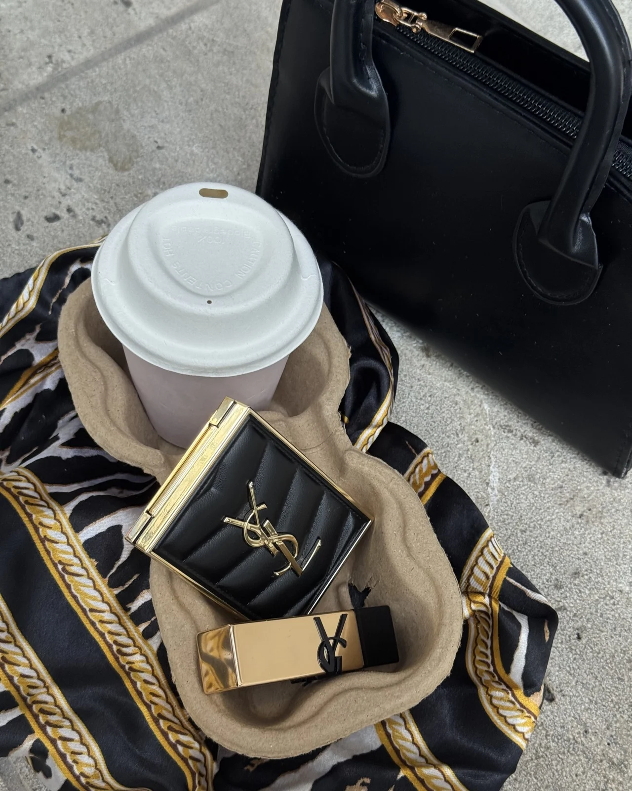Coffee, a handbag and accessories arranged on a café chair